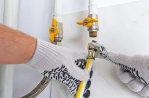 Adjustable wrench in hand of maintenance engineer for replacing reinforced propane gas hose due to gas leak at home boiler room.